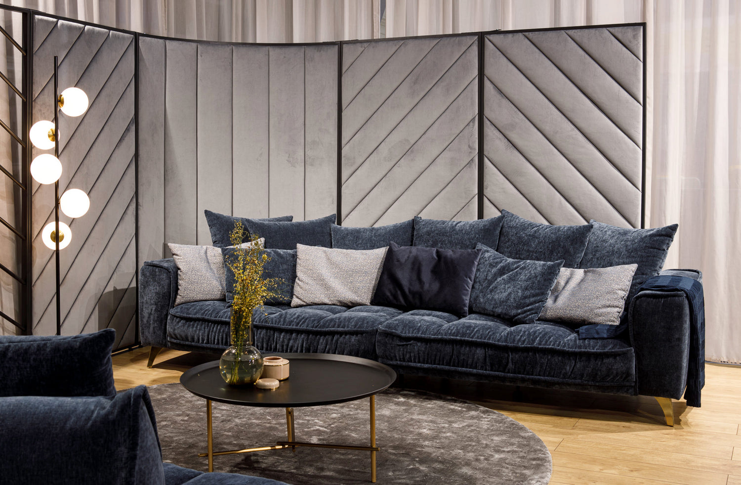 Tamsiai mėlyna sofa su pagalvėlėmis jaukioje svetainėje