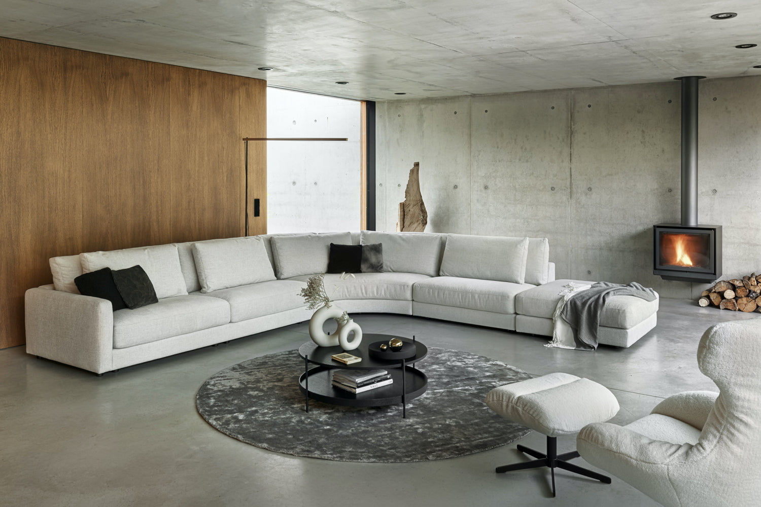 Didelė šviesi modulinė kampinė sofa erdvioje svetainėje su židiniu